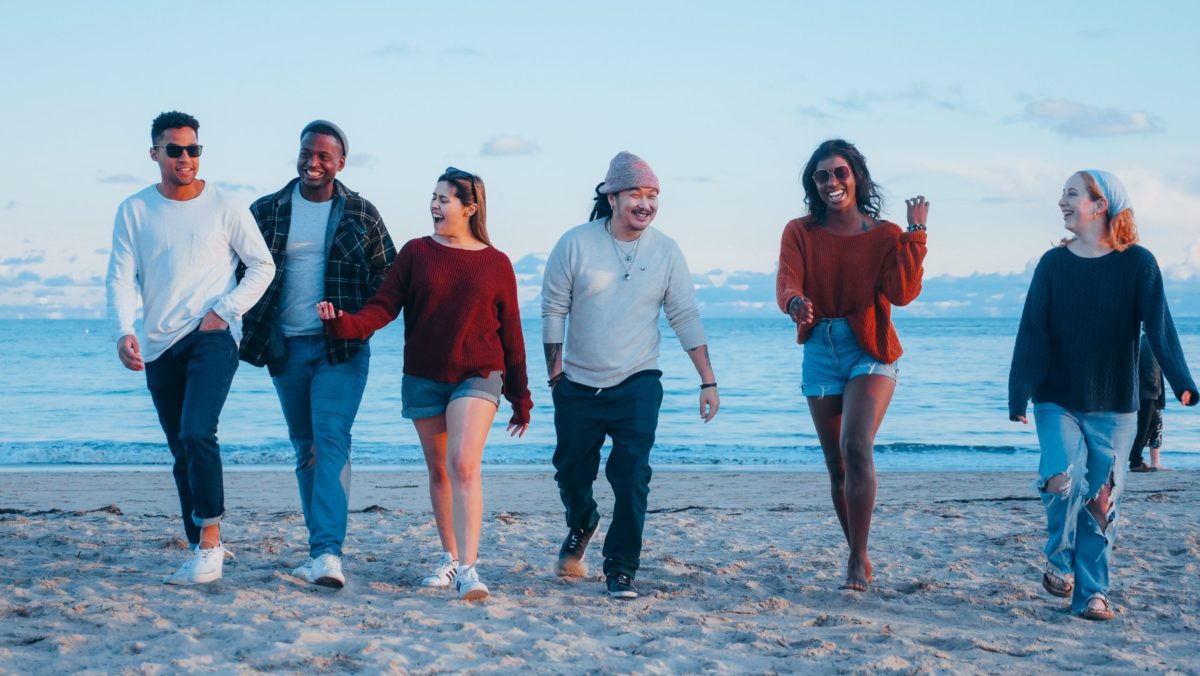 Group of happy friends walking on the beach